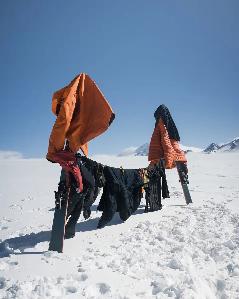 Wet climbing clothes drying on makeshift line in snowy mountain landscape