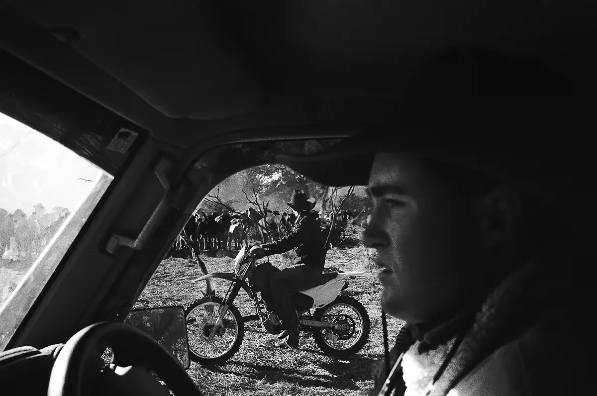 View through car window of person on motorcycle in rural landscape