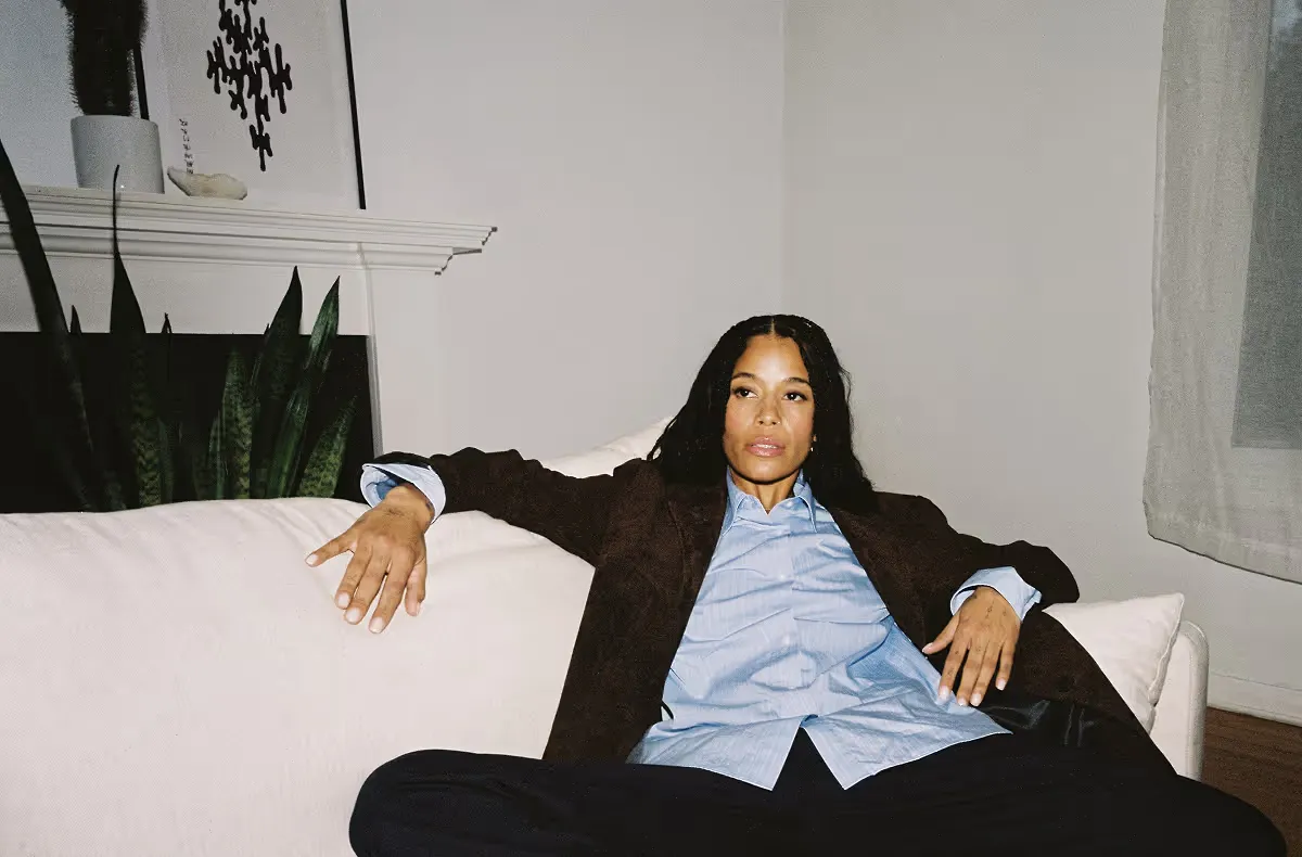 Woman in brown blazer and blue shirt relaxing on white couch