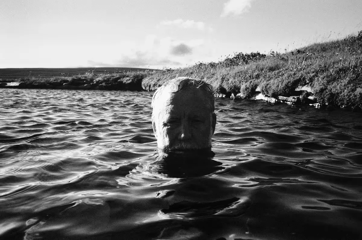 Geoff's head emerging from water near grassy shoreline