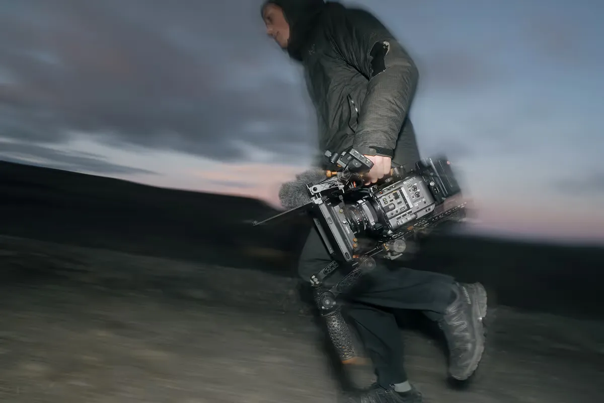 Cinematographer with stabilized camera rig filming at dusk in motion