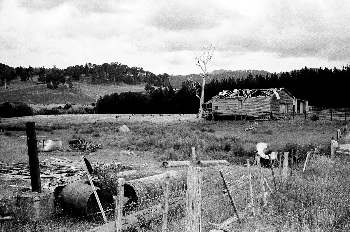 Abandoned weathered homestead with collapsed roof in rural landscape